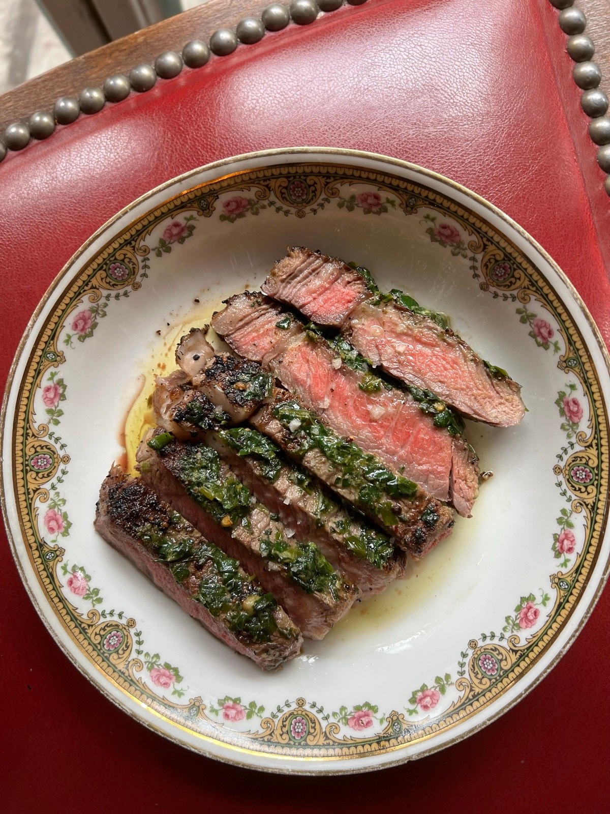 Sliced steak with salsa verde on a vintage plate
